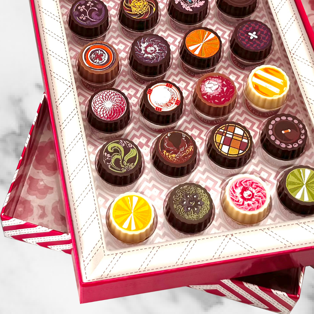 Open Timothy Adams Twenty-Four-Piece Gourmet Chocolate Gift Box with assorted artisanal bonbons in signature patterned packaging.