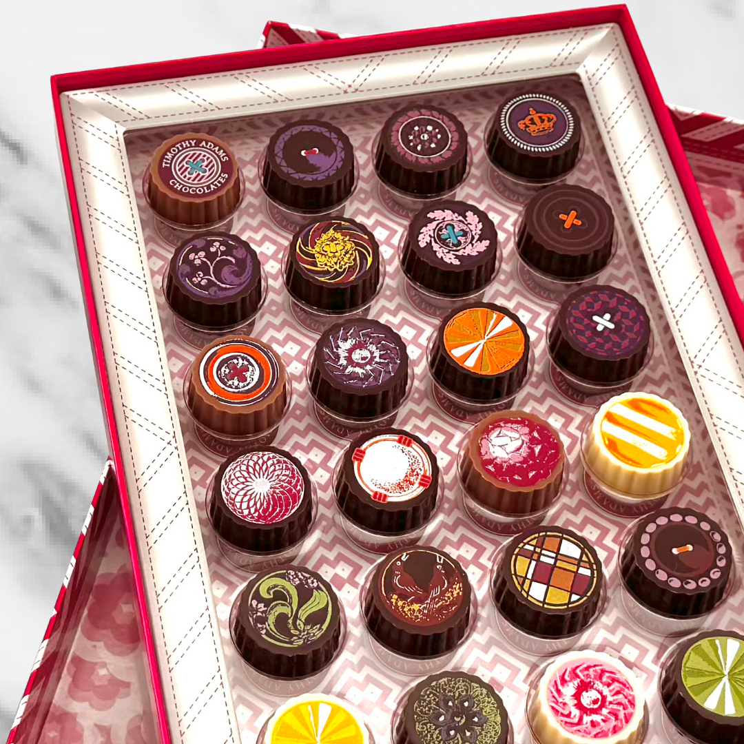 Timothy Adams Twenty-Four-Piece Chocolate Collection showcasing an assortment of hand-painted bonbons in a luxury red gift box.